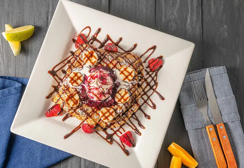 French toast slices topped with fresh seasonal berries and maple syrup